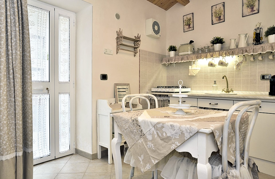 Cucina bianca con tavolo, sedie e scaffali in stile shabby chic