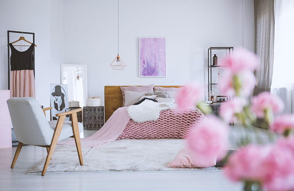 Camera da letto in stile scandinavo romantico, con fiori rosa in primo piano e dettagli in rosa