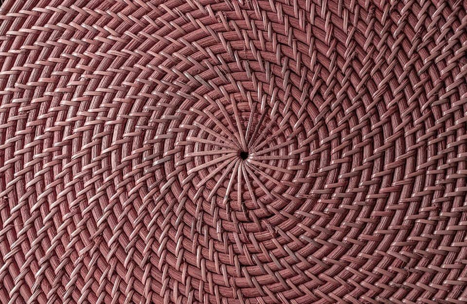Dettaglio dell'intreccio di un cesto in vimini verniciato di rosa con un pattern a spirale