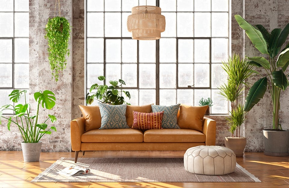 Salotto moderno con sofà, grande lampadario in vimini e finestra di ampie dimensioni. L'ambiente è arredato con molte piante