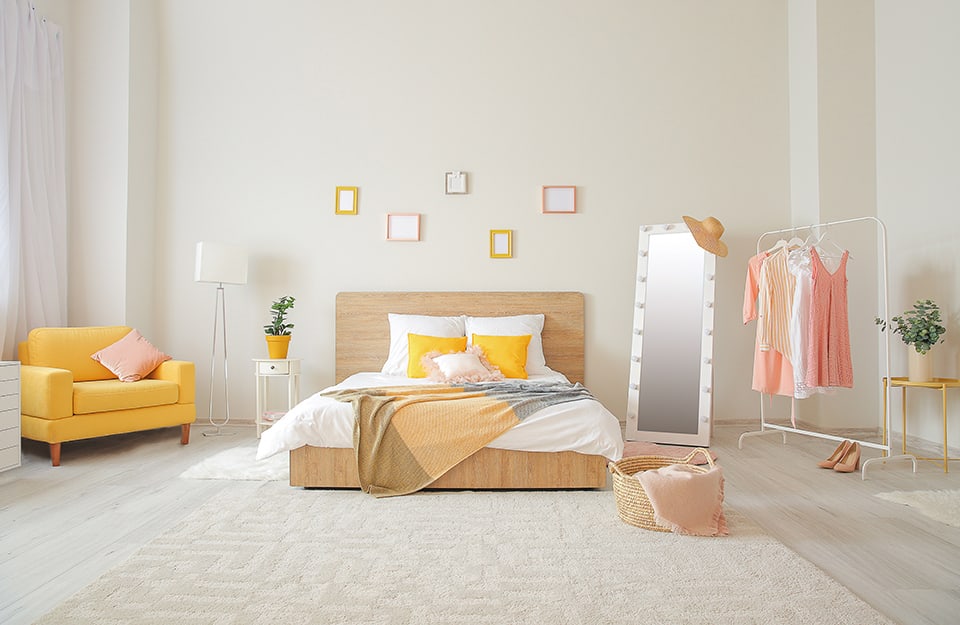 Camera da letto spaziosa, luminosa e minimale, con colori chiari e toni d'accento in giallo