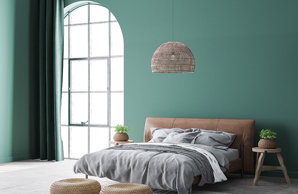 Luminosa camera da letto con pareti verdi. C'è un grande finestrone ad arco e c'è un lampadario sopra al letto