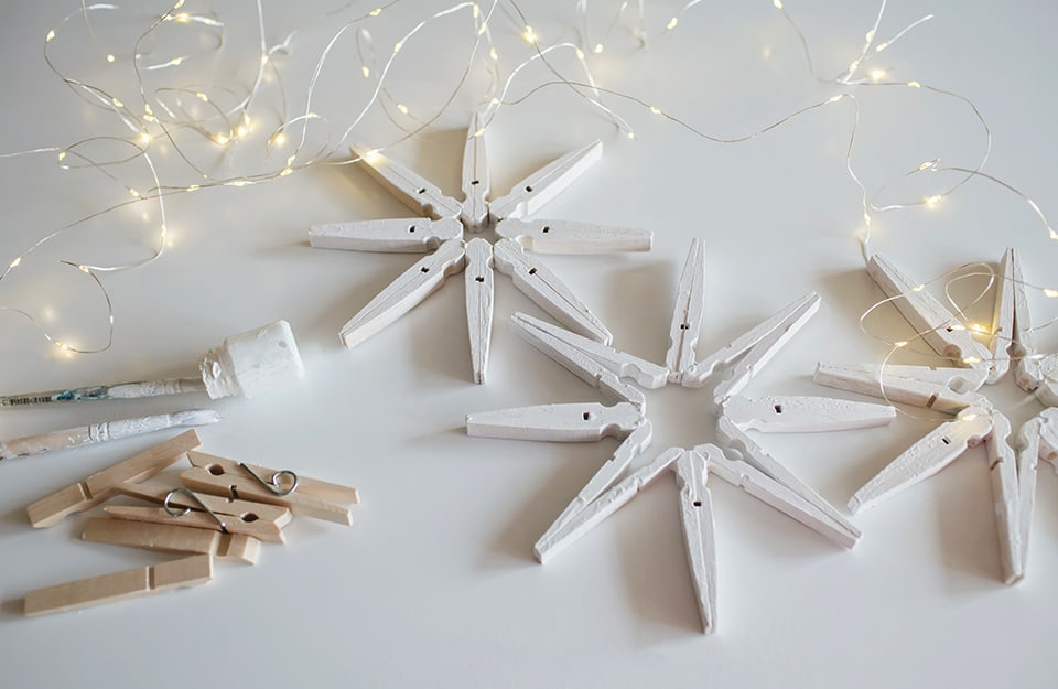 Delle stelle natalizie o dei fiocchi di neve creati attaccando insieme vecchie mollette di legno