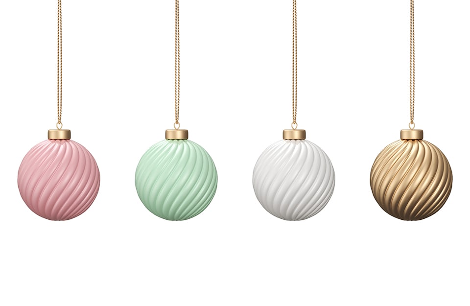 Quattro palle di Natale di colori diversi (rosa pastello, verde pastello, bianco e dorato) su sfondo bianco