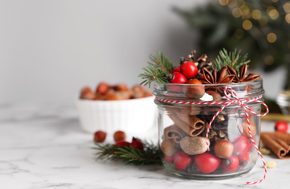 Un vasetto di vetro riempito di pigne, bacche, anice stellato e cannella come decorazione natalizia