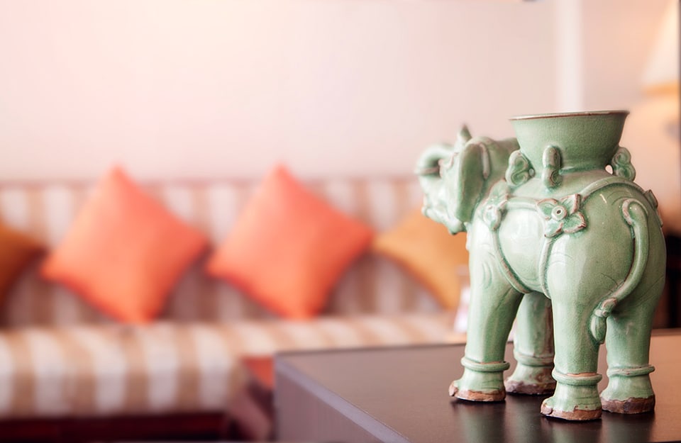 Statuetta etnica elefante e, sullo sfondo, un divano in stile etnico