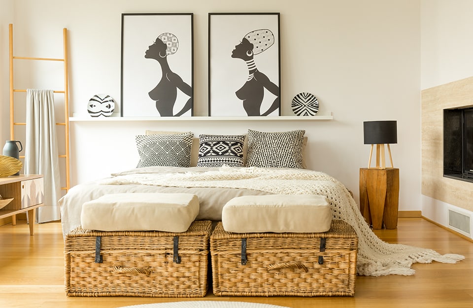Camera da letto minimale sui toni del legno e dell'écru con elementi etnici in bianco e in nero che richiamano l'Africa