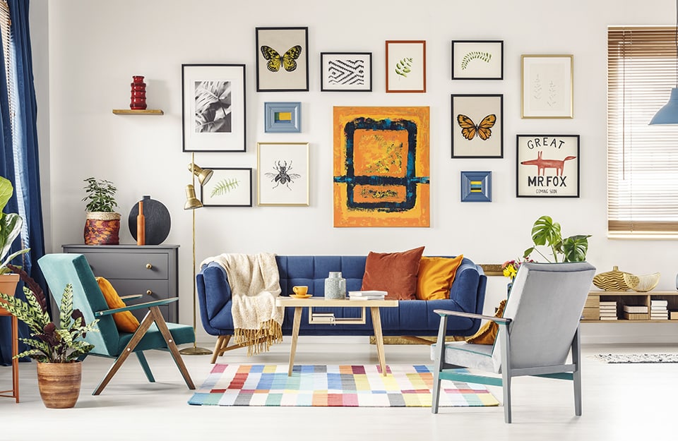 Salotto moderno con parete sopra il sofà decorata a “gallery wall”, cioè una composizione di quadri e immagini di differenti dimensioni e soggetti
