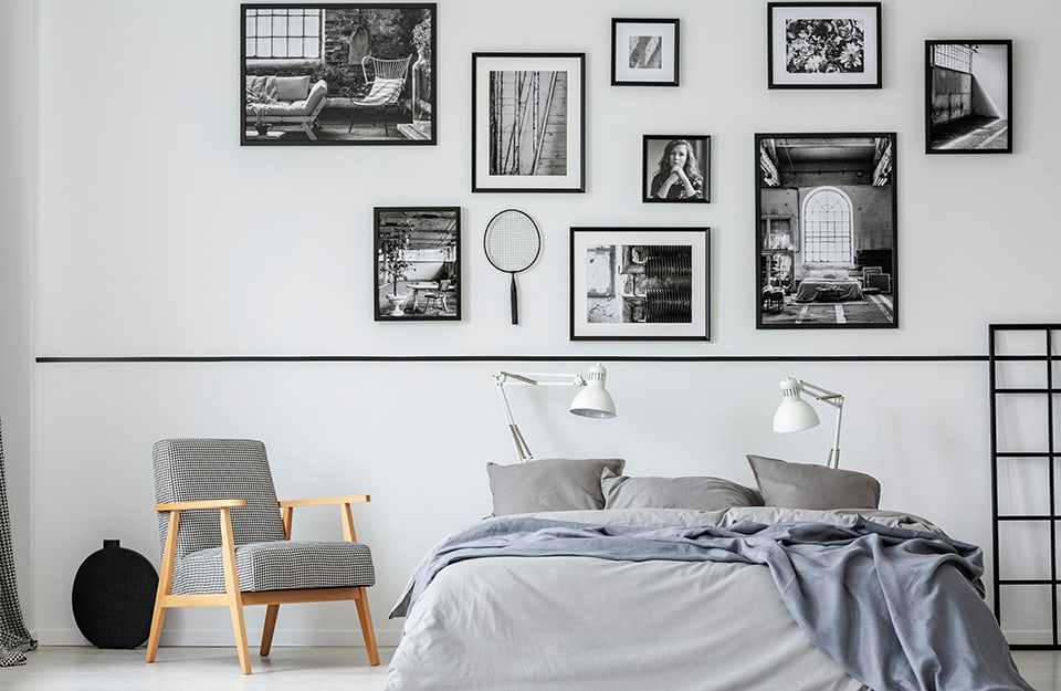 Camera da letto con parete decorata con una composizione di molte fotografie in bianco e nero