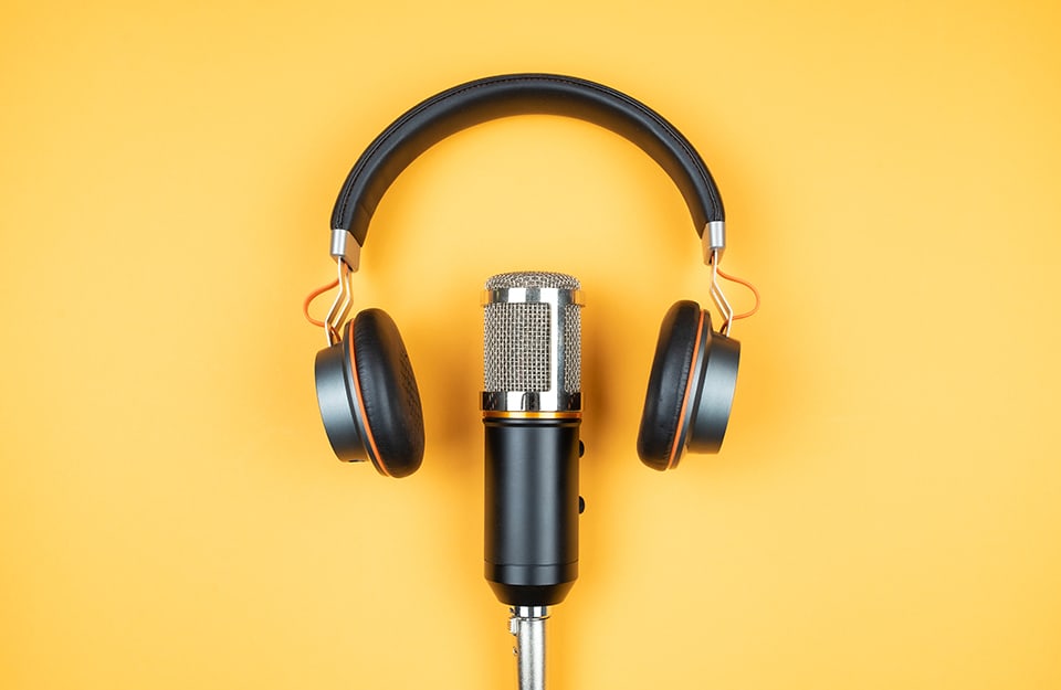 Cuffie e microfono su fondo giallo, per simboleggiare i podcast