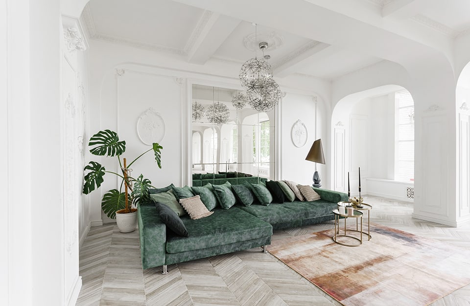 Salotto in stile barocco moderno, con grande sofà verde in tessuto marmorizzato, parquet chiaro a spina di pesce, pareti bianche stuccate, tavolini da caffè moderni metallizzati e grandi lampadari metallici a globo