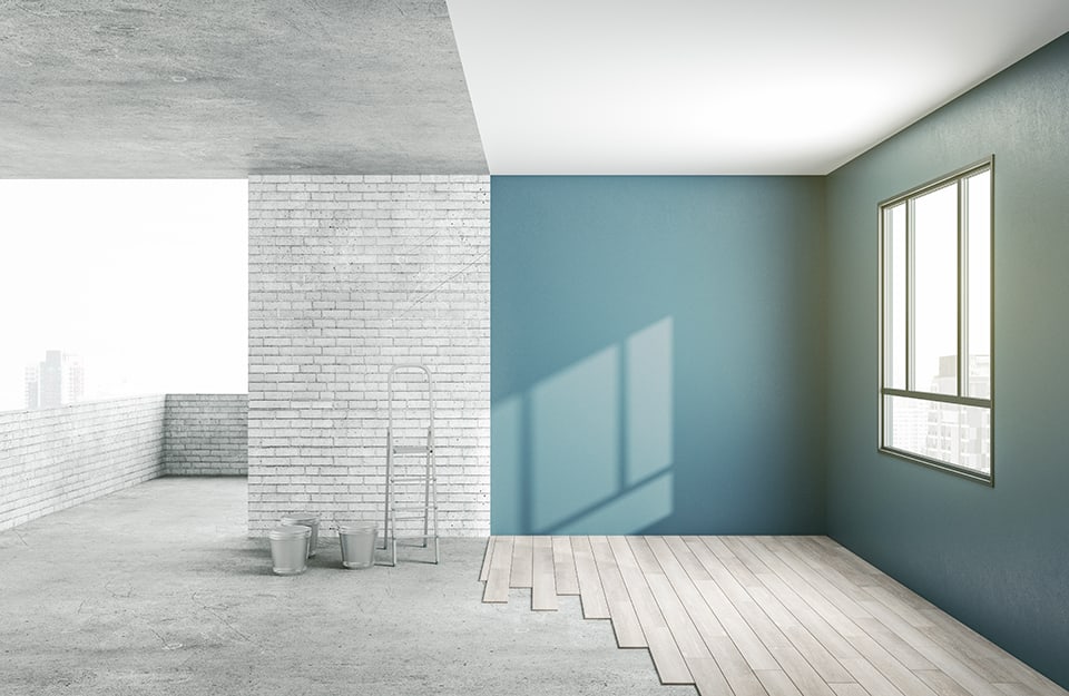 Casa in corso di ristrutturazione: metà dell'immagine vede lo spazio ancora grezzo mentre nell'altra le pareti sono verniciate di verde-azzurro, il soffitto di bianco e il pavimento è in parquet chiaro
