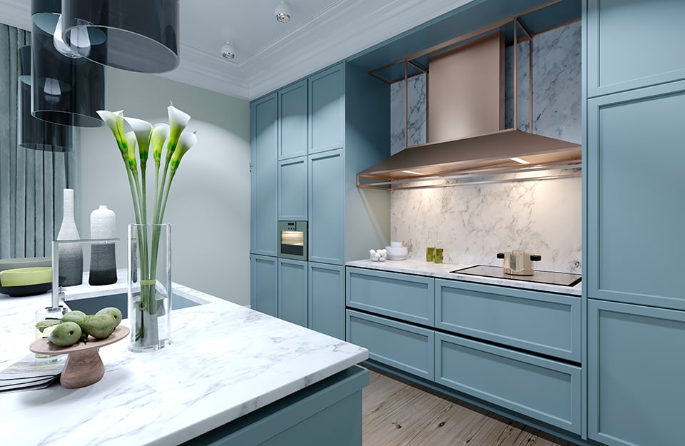 Cucina moderna componibile sui toni del blu-azzurro: in primo piano c'è un isola con accessori e un vaso di fiori