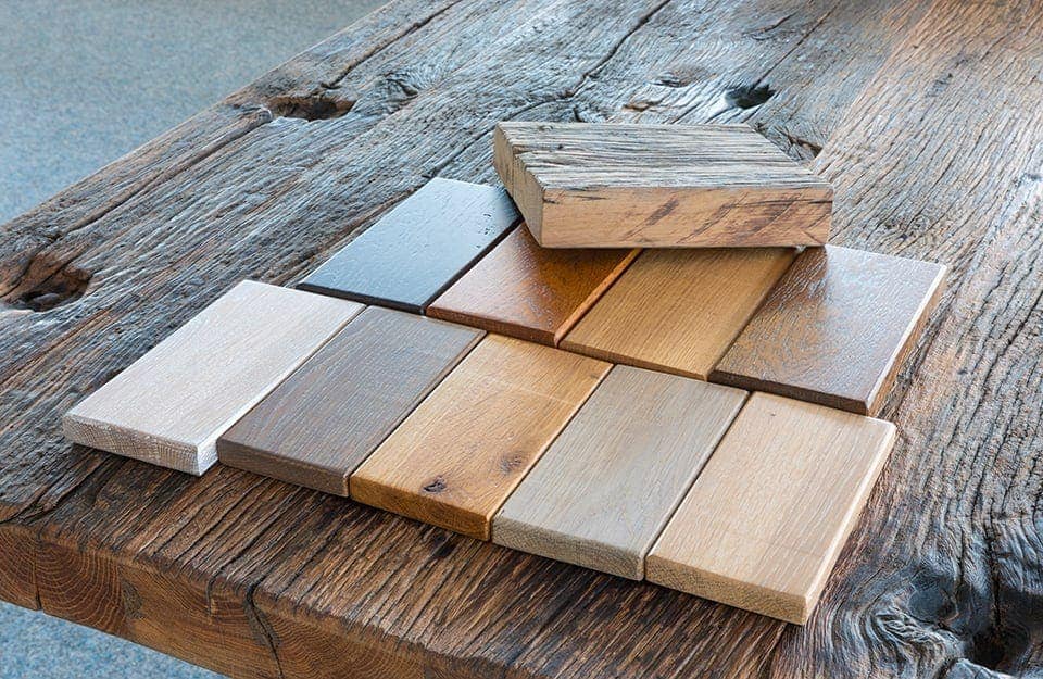 Vecchio tavolo in legno con sopra appoggiati diversi campioni di legno per arredi, con colori e texture differenti
