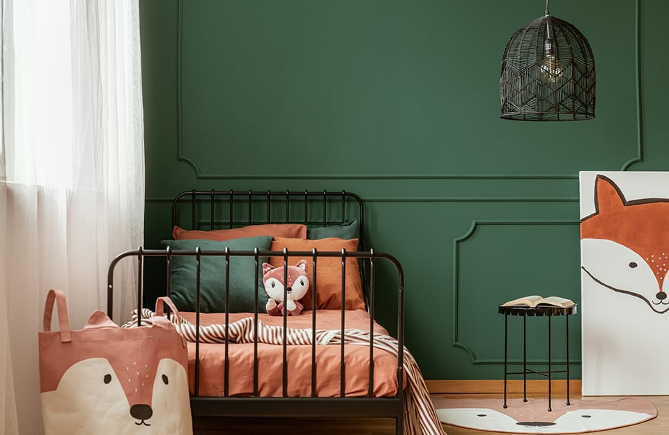 Children's room with black metal furniture, green wall decorated with classical motifs, black cage chandelier and many fox-face decorations;