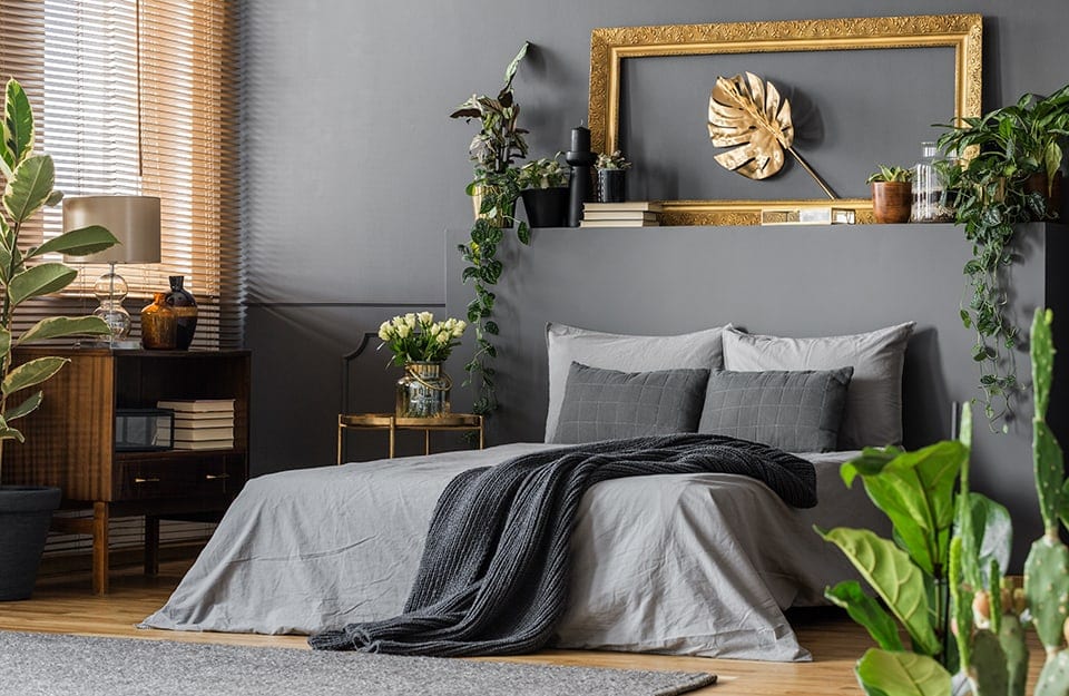 Camera da letto sui toni del grigio, con parete grigia, letto con biancheria grigia.