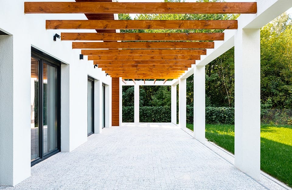 Pergolato in legno nel giardino di una casa moderna con muri e colonne bianche