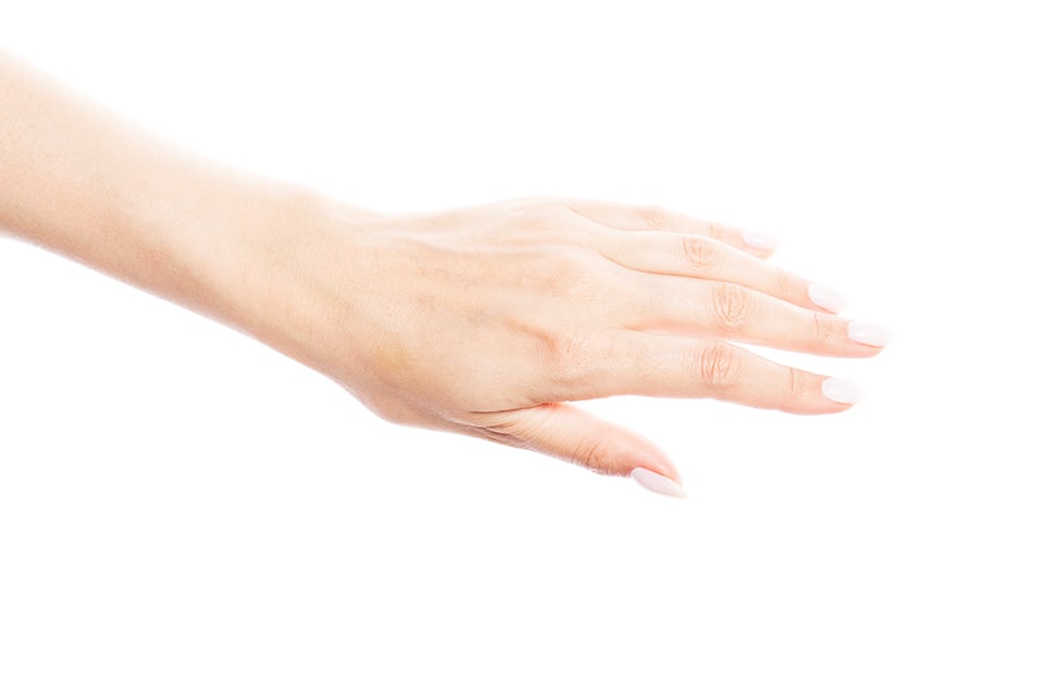 Una mano femminile con unghie smaltate di bianco su sfondo bianco