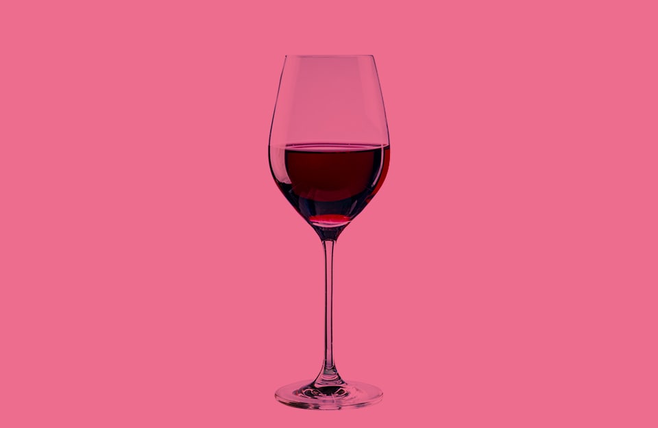 Un bicchiere di vino rosso su sfondo rosa