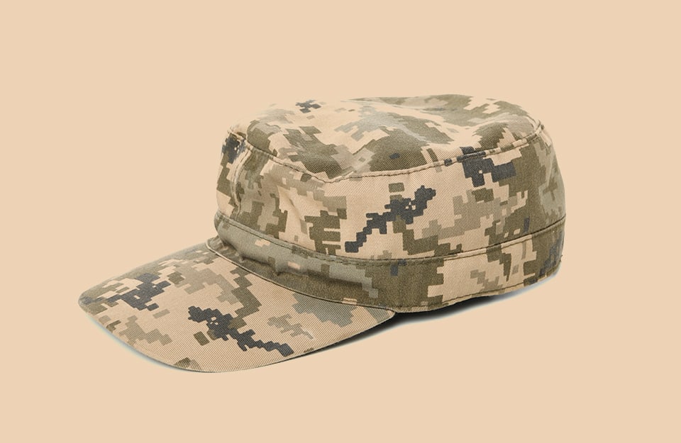 Un cappello militare mimetico su sfondo color cachi