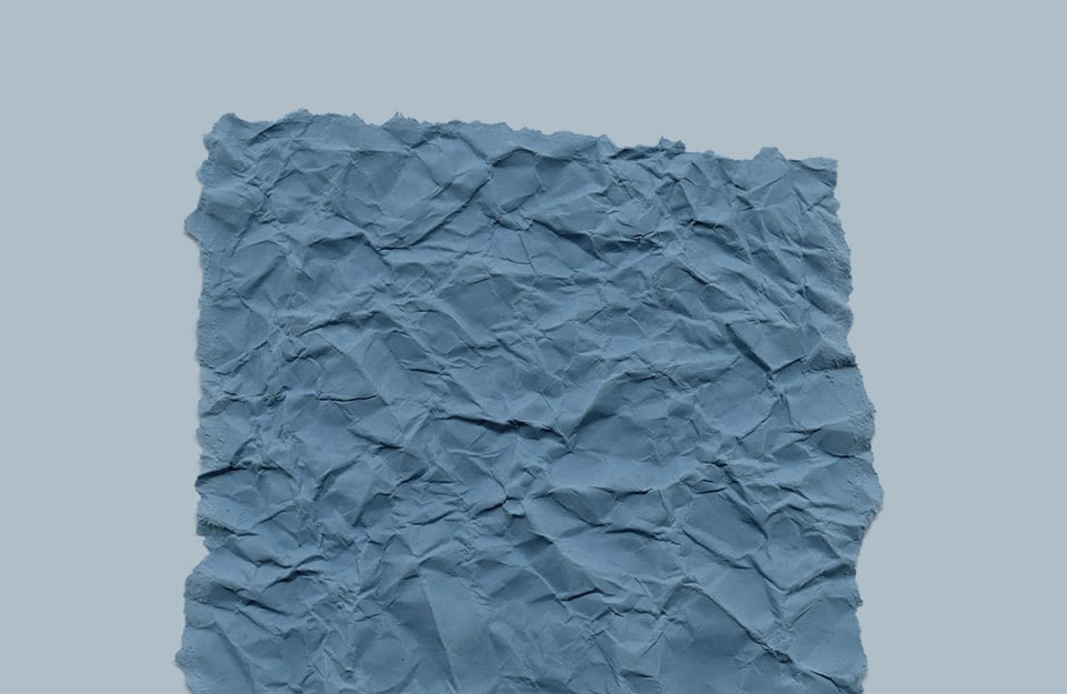 Un foglio spiegazzato color carta da zucchero su sfondo grigio-azzurro