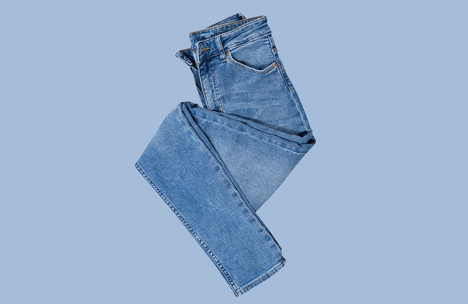 Un paio di jeans ripiegati a formare una specie di zeta, su sfondo color denim