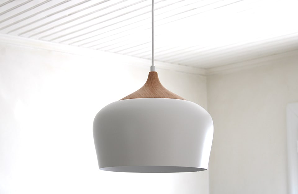 Una lampada a sospensione dalle linee curve in stile scandinavo, in ceramica bianca e legno