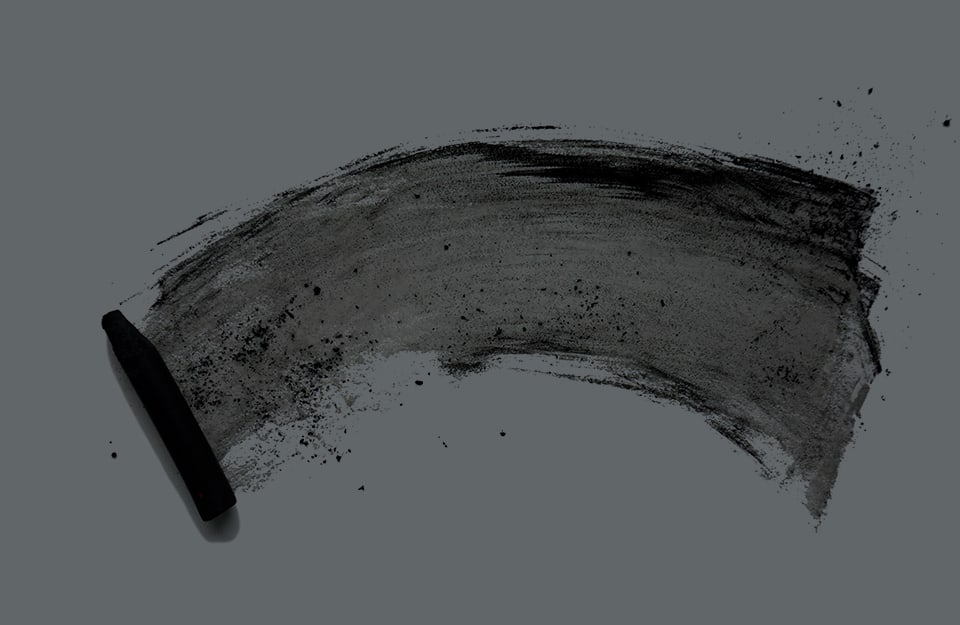 Un carboncino con la sua traccia su un foglio scuro