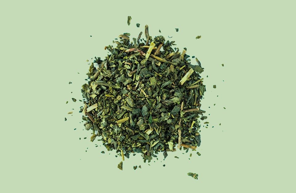 Delle foglie di tè sminuzzate su sfondo color grigio tè verde