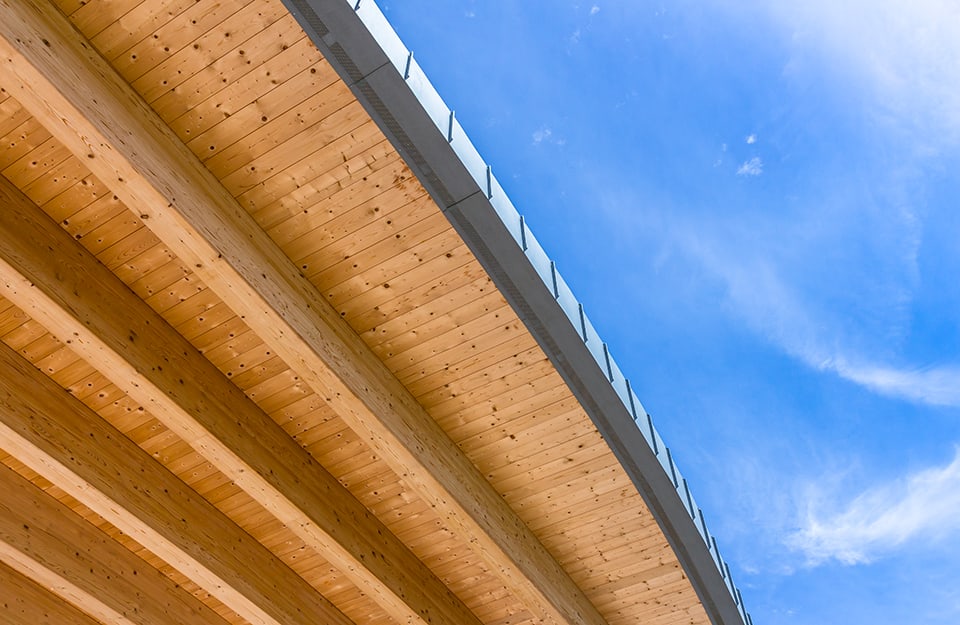 Vista dal basso di un grande tetto in legno, con travi e perline
