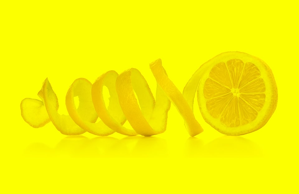 Un limone sbucciato a spirale su sfondo giallo limone