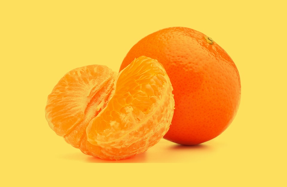 Un mandarino intero e un mezzo mandarino sbucciato, su sfondo color mandarino