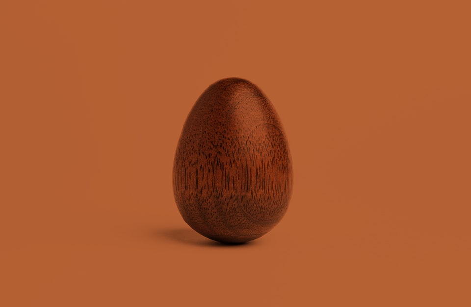 Un uovo in legno di mogano, su sfondo marrone
