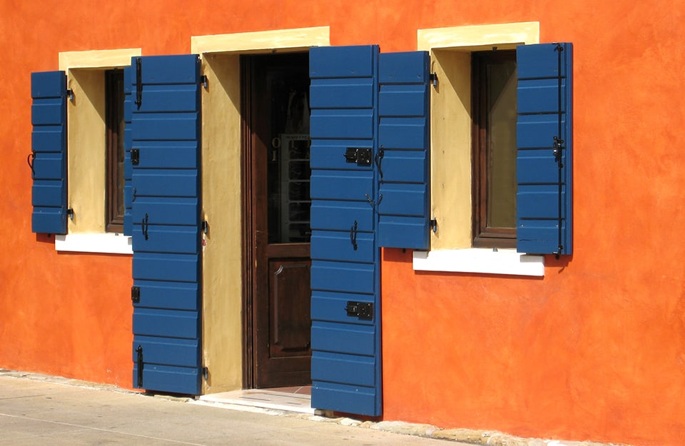 Finestre e porta d'entrata di un negozio in un palazzo con muro arancione e scuri in alluminio blu, nuovi