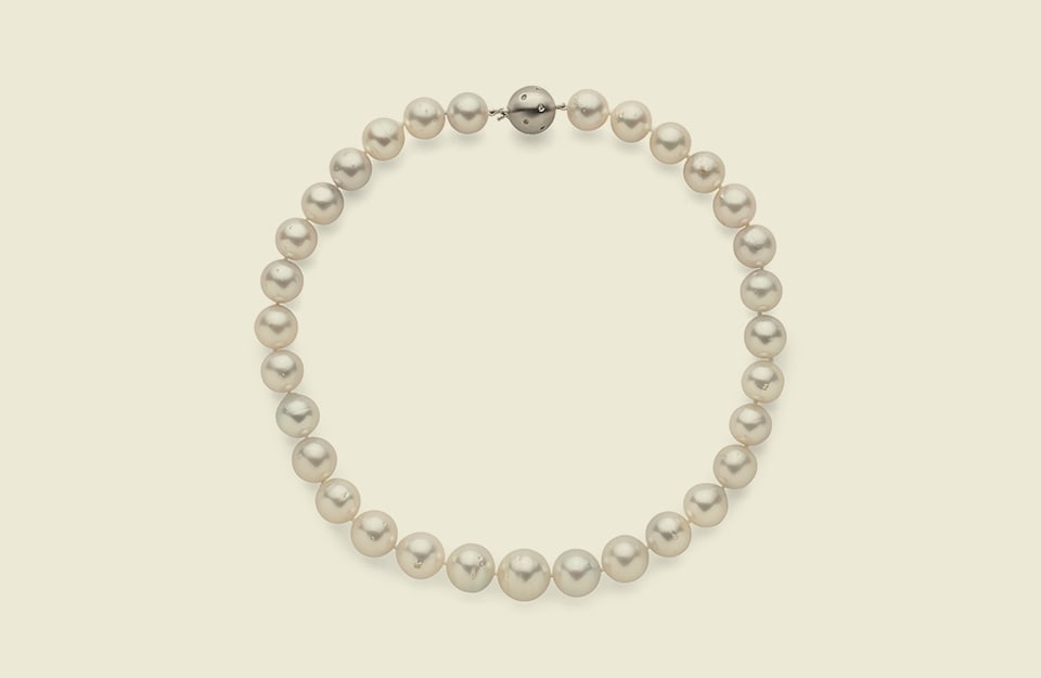 Un bracciale di perle su sfondo bianco perla
