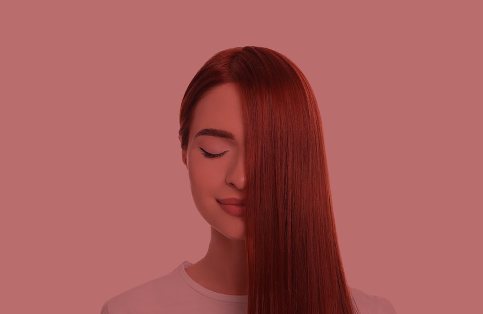 Una ragazza con lunghi capelli rossi, pettinati in modo tale che per metà coprano il volto, su sfondo rosso Tiziano