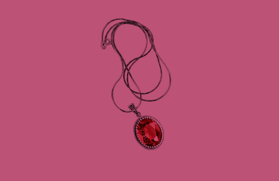 Una collana con rubino, su sfondo magenta scuro