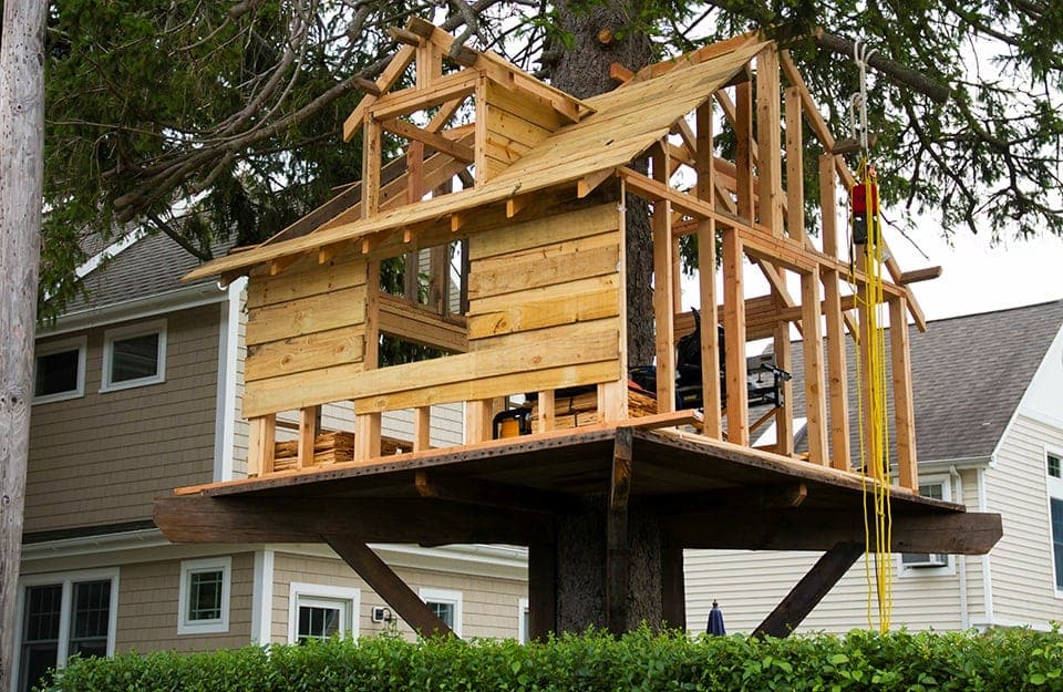 Una casa sull'albero in legno in costruzione nel giardino di una grande casa