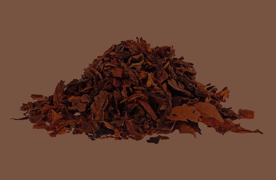 Un mucchietto di foglie di tabacco essiccate su sfondo marrone