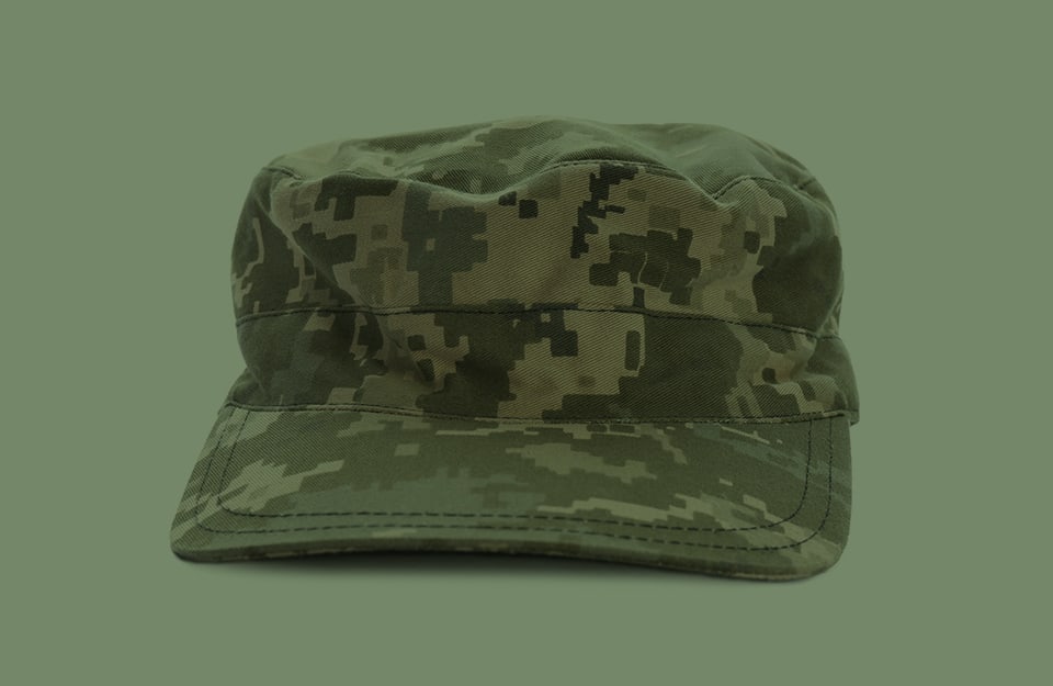 Un berretto con visiera in colori mimetici su sfondo verde mimetico