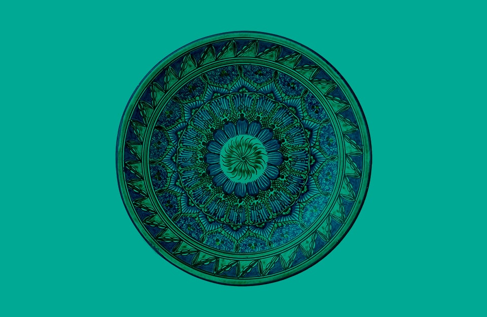 Un piatto di ceramica persiano decorato, su sfondo verde
