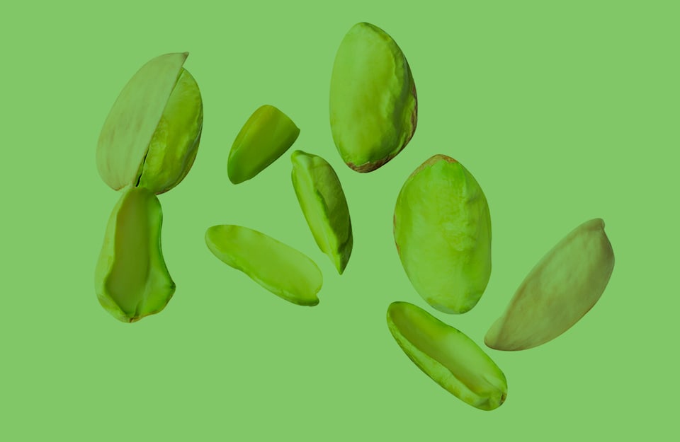 Dei pistacchi, sgusciati e non, su sfondo verde chiaro