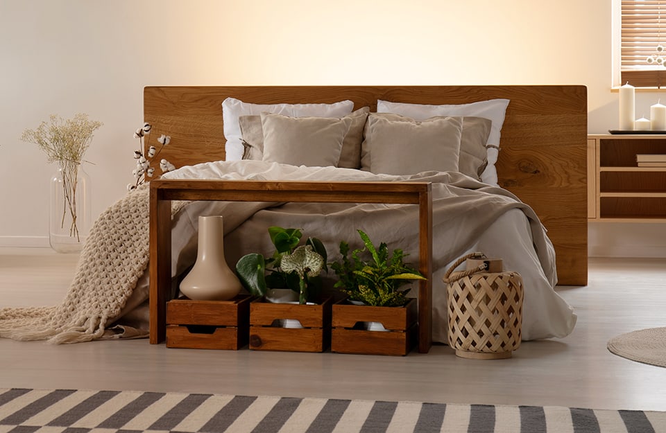 Camera da letto con ai piedi del letto un mobiletto con dentro cassette di legno che contengono vasi e piante