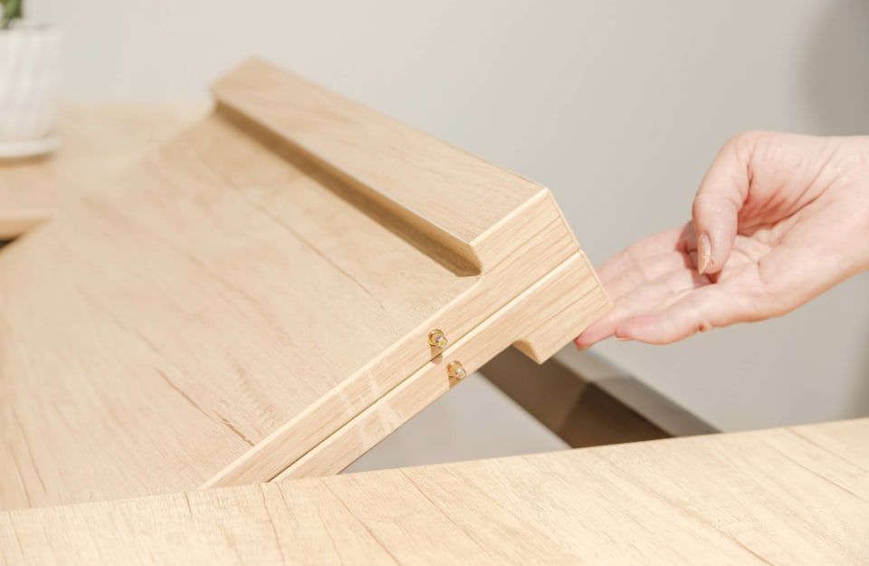 Dettaglio su una mano di donna che sta sollevando la prolunga di un tavolo allungabile in legno
