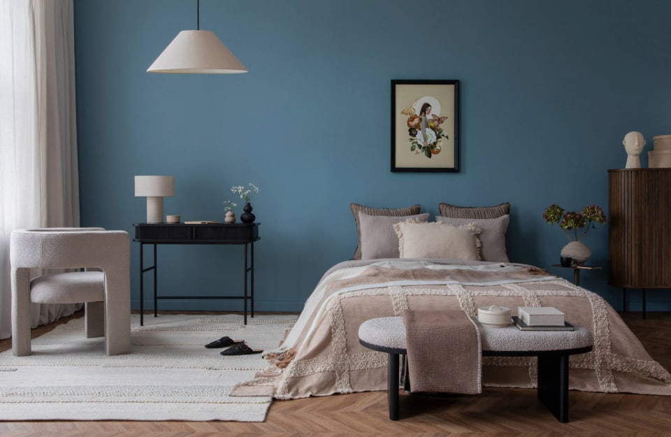 Camera da letto con pareti blu e arredi in tonalità écru