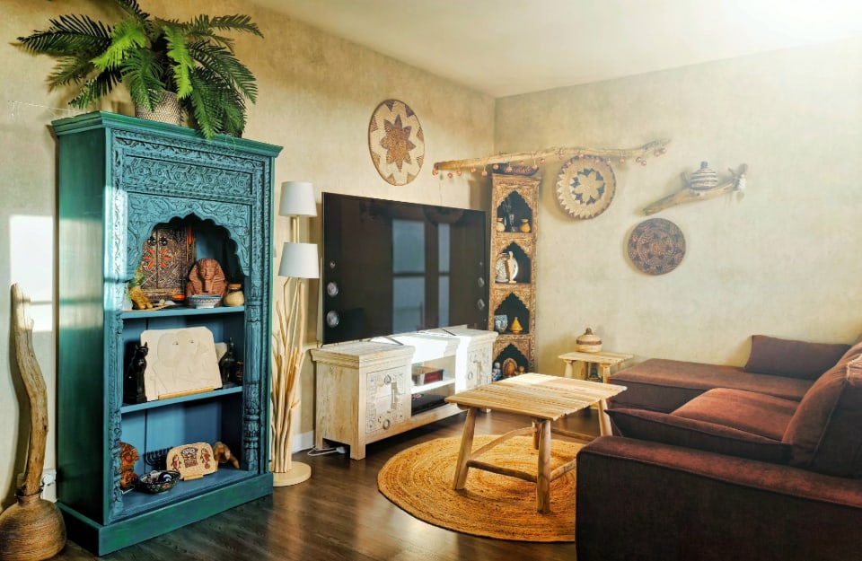 Salotto in stile etnico, con libreria e mobile tv in legno lavorato e decorato, lampade fatte a mano e piatti decorativi alle pareti