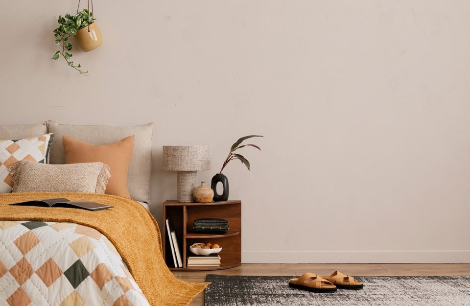 Habitación con base neutra y acentos mostaza/terracota en plaid y cojines. Ejemplo de toques especiados bien dosificados.