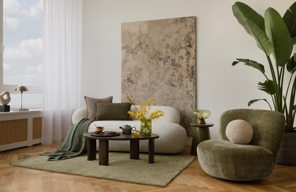 Living con linee morbide e palette neutra, poltrona verde oliva e divano curvo