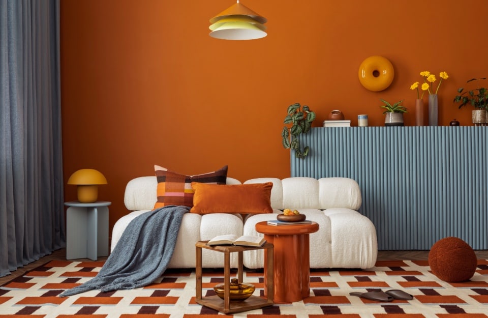 Living contemporaneo parete terracotta mobile azzurro polveroso contrasto materico interior design