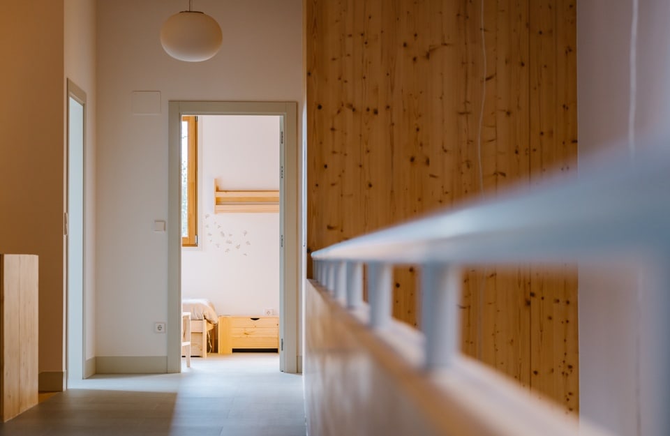 Corridoio con rivestimento in legno e camera sullo sfondo